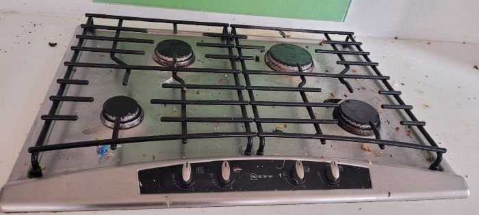 Greasy and dirty stovetop before deep cleaning as part of an end of tenancy cleaning project.