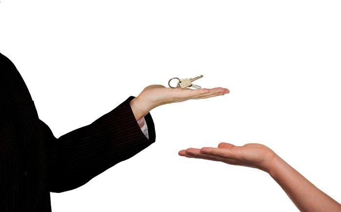 Handing over keys, symbolizing the importance of meeting landlord requirements for end of tenancy cleaning to ensure a smooth move-out and deposit return.