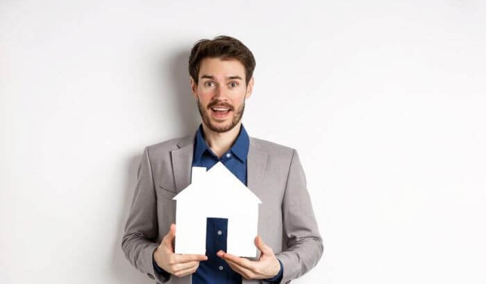 A person holding a house model, representing the importance of being present during the final walk-through of a property.