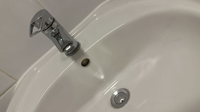 Bathroom fixtures covered in limescale before detailed cleaning, showing soap scum buildup on tiles, ready for a meticulous revamp.