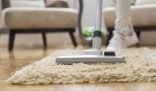 A person vacuuming a beige carpet, representing a quick and efficient 30-minute whole house cleanup strategy.