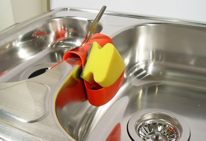 A clean, shiny kitchen sink with a sponge and scrubber, illustrating effective methods for keeping the sink and dishes clean.