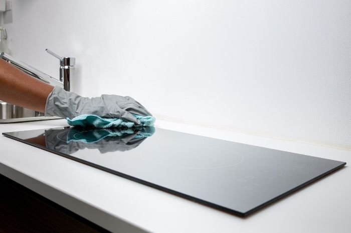A professional cleaner wearing gloves and wiping down a kitchen surface, demonstrating thoroughness and attention to detail essential for end of tenancy cleaning.
