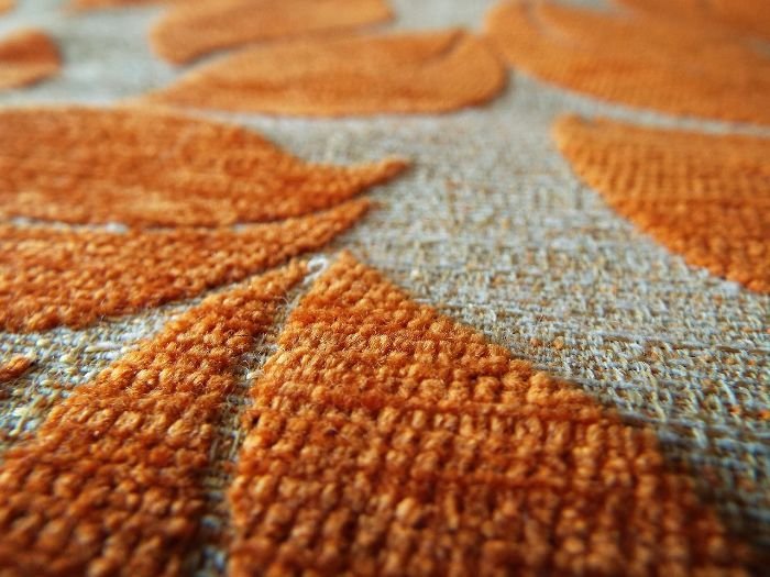 Close-up of a clean, orange-patterned carpet, emphasizing the importance of vacuuming and steam cleaning during an end of tenancy cleaning in London.
