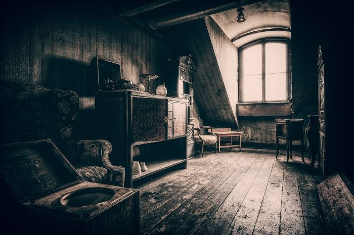 Old attic filled with various items, illustrating the need for decision-making on what to keep, donate, or discard for effective attic organization