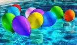 Vibrant colorful balloons floating on a swimming pool surface, setting a festive mood for a party