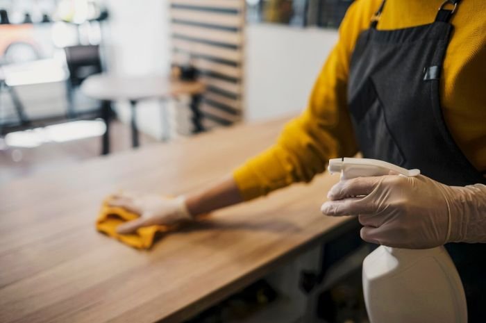 Person wiping down kitchen counter as part of decluttering living spaces, focusing on maintaining cleanliness and organization in home interiors