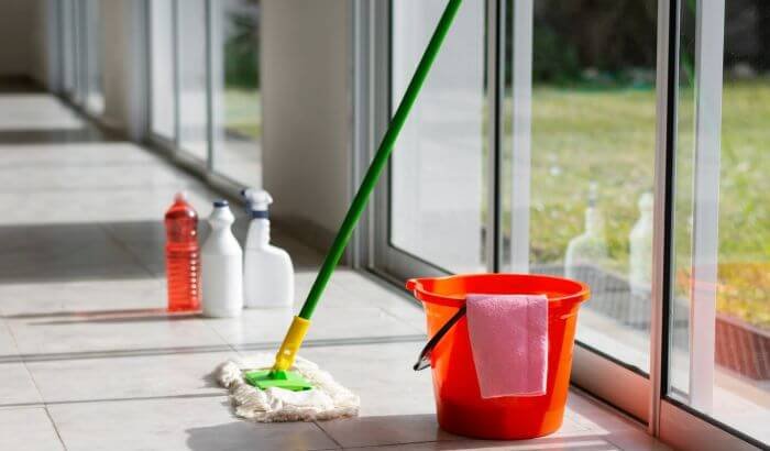 Cleaning tools ready for end-of-summer tasks with mop and bucket on a sunlit patio, preparing for the fall season