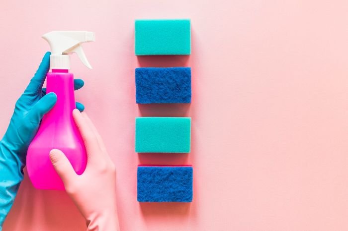 Cleaning supplies with reusable cloths and refillable spray bottles, emphasizing the importance of reducing single-use items in sustainable practices.