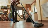Two people efficiently cleaning a spacious living room using a vacuum and mop, showcasing essential tools for DIY cleaning that save time and effort.