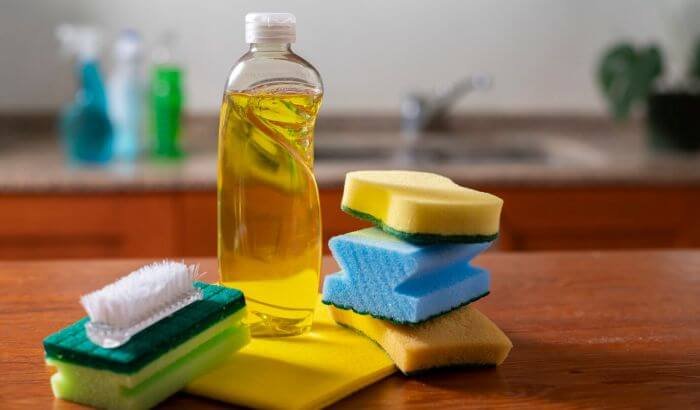 All-purpose cleaner with sponges and scrub brushes on a kitchen counter, ideal for tackling various household cleaning tasks.