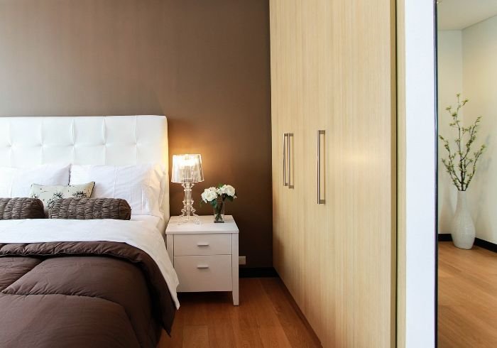 Clean and organized bedroom with neutral tones, highlighting summer maintenance tips for keeping bedrooms and living rooms comfortable and tidy.