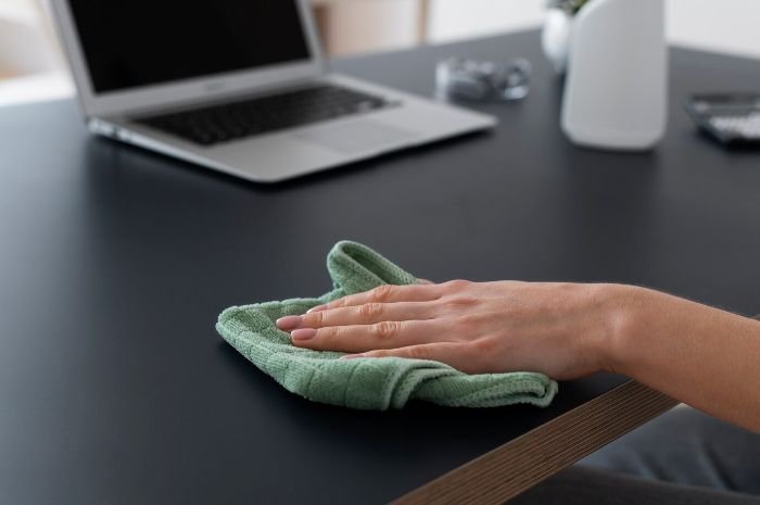 Using a microfiber cloth on a smooth surface like a desk for streak-free and scratch-free cleaning
