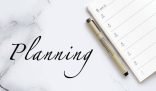 Planner and pen on a marble surface, emphasizing the importance of creating a custom cleaning plan tailored to your home’s needs.