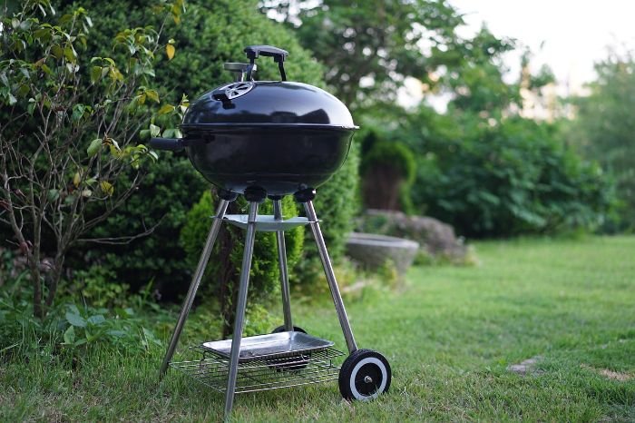 Black outdoor grill on a lawn, emphasizing the importance of deep cleaning grills and cooking areas for better performance and food quality during summer.