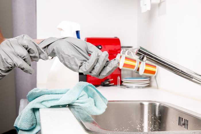Rubber Gloves - Your Trusted Tool for Safe and Effective Cleaning 4 Person using environmentally friendly biodegradable gloves while cleaning a kitchen sink.