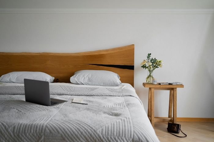 Modern bedroom with a wooden headboard, cozy bedding, and a bedside table, illustrating the spring refresh for a clean and stylish living space.