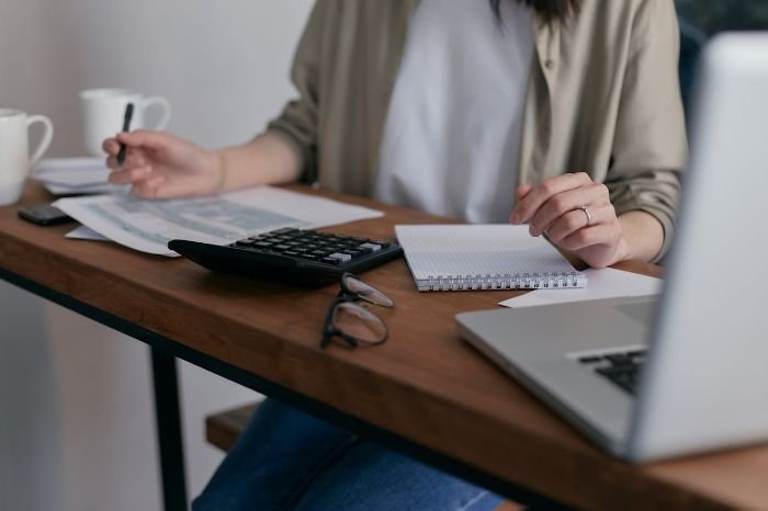 A person using a calculator and taking notes, representing cleaning companies adjusting service prices to maintain quality and fair wages after minimum wage increases.