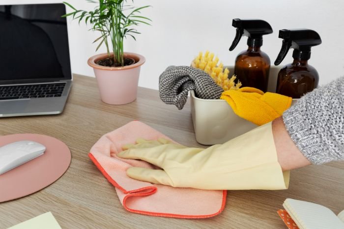 Person cleaning a desk with hydrogen peroxide, demonstrating the benefits of using eco-friendly, germ-killing solutions for home cleaning.