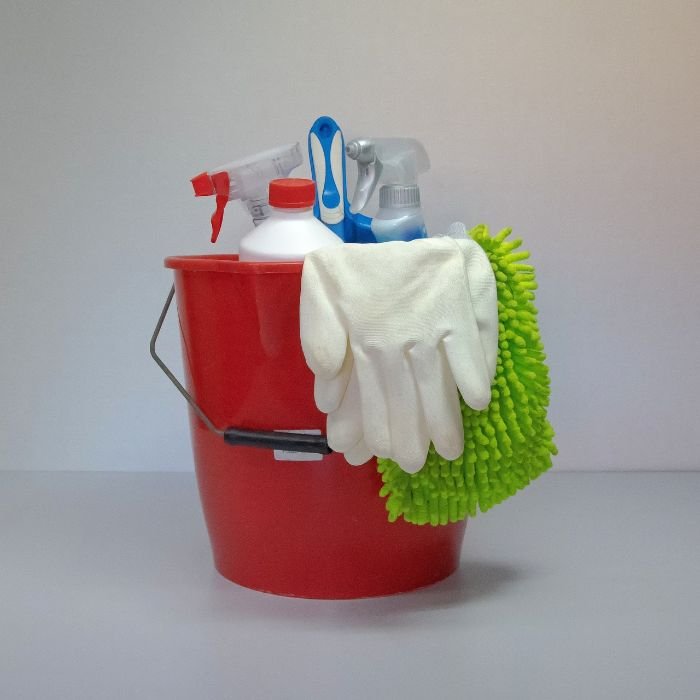 Cleaning bucket filled with eco-friendly cleaning products, spray bottles, gloves, and a microfiber mop, illustrating best practices for reducing water use in green cleaning.