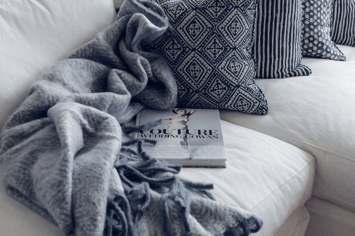 Cozy throws and blankets on a sofa, demonstrating the importance of cleaning and maintaining winter-specific items like blankets and throws during the colder months.