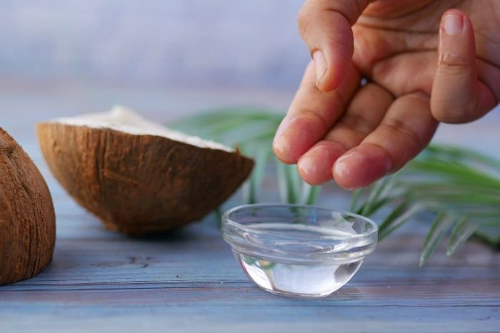 Hand applying coconut oil on wood, demonstrating proper techniques to avoid common mistakes when polishing wooden surfaces.