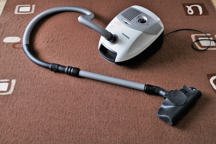 Canister vacuum cleaner on a brown carpet used to explain different types of vacuum cleaners and their features.