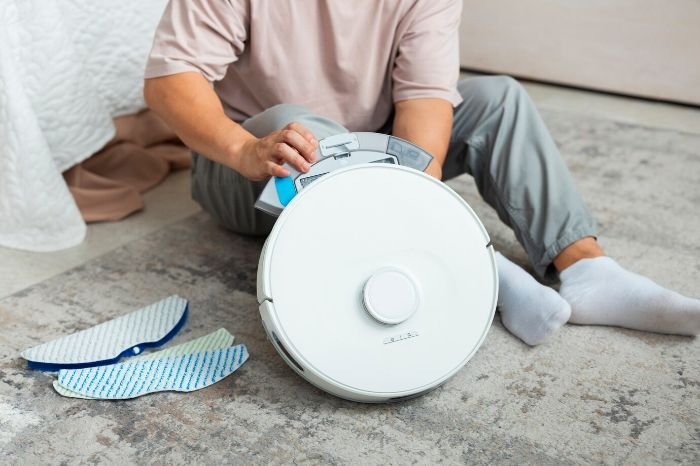 Person maintaining a vacuum cleaner by replacing parts, illustrating tips for regular maintenance like cleaning, filter changes, and part replacements for long-term use.