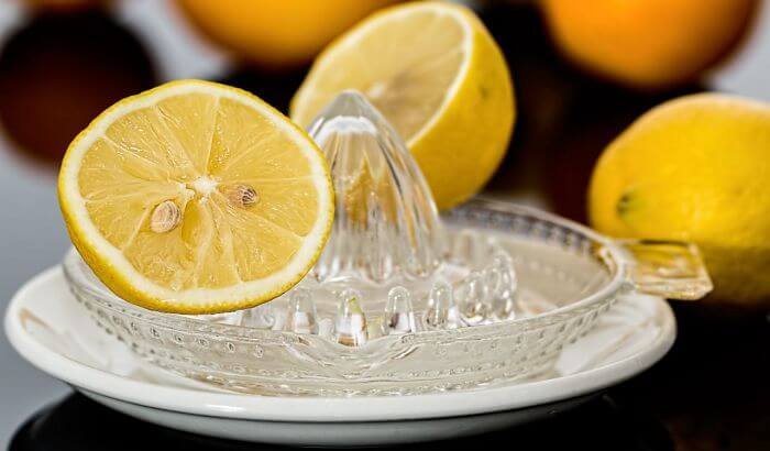 Freshly squeezed lemon juice showcasing its natural power for stain removal and bleaching, with lemons and a glass juicer in the background.