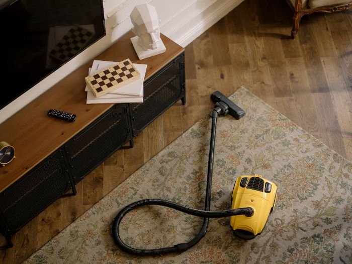 Vacuum cleaner on a carpet in a London living room, symbolizing the impact of minimum wage increases on cleaning service prices.