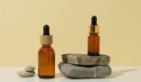 Essential oils in amber glass bottles displayed on stacked stones, used for effective natural cleaning solutions.