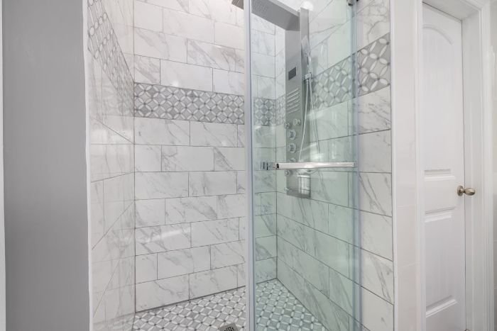 A sparkling clean bathroom shower with white and patterned tiles, highlighting the importance of deep cleaning and grout care in high-humidity areas to prevent mold and discoloration.