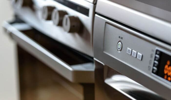 Close-up view of modern kitchen appliances, including a stainless steel oven and dishwasher, highlighting the importance of regular cleaning for functionality and hygiene.