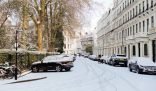 Snow-covered London street with parked cars, highlighting seasonal considerations for end of tenancy cleaning in winter
