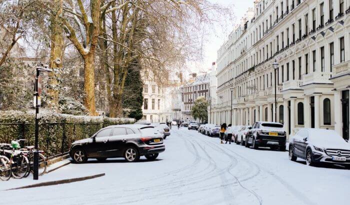 Snow-covered London street with parked cars, highlighting seasonal considerations for end of tenancy cleaning in winter