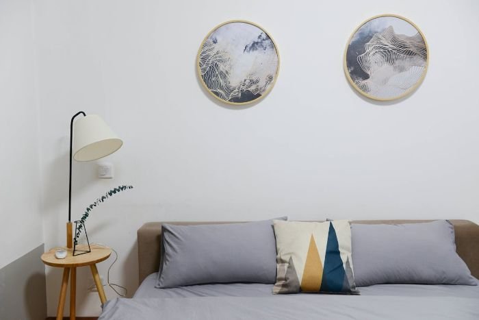 Minimalist bedroom with clean bedding and decor, illustrating factors that affect end of tenancy cleaning time, such as property condition and accessibility.