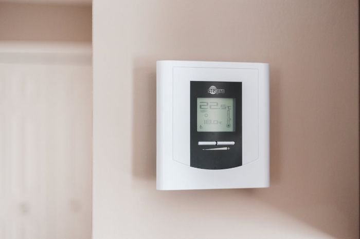 Smart thermostat on wall controlling home temperature and air quality for optimized cleaning effectiveness.