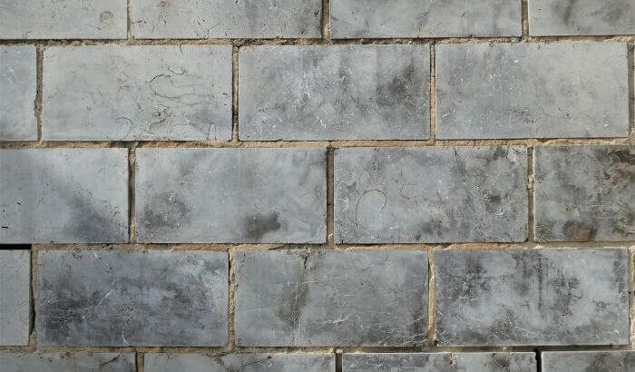 Close-up of dirty bathroom tiles and grout, emphasizing the importance of regular cleaning to prevent buildup and maintain hygiene.