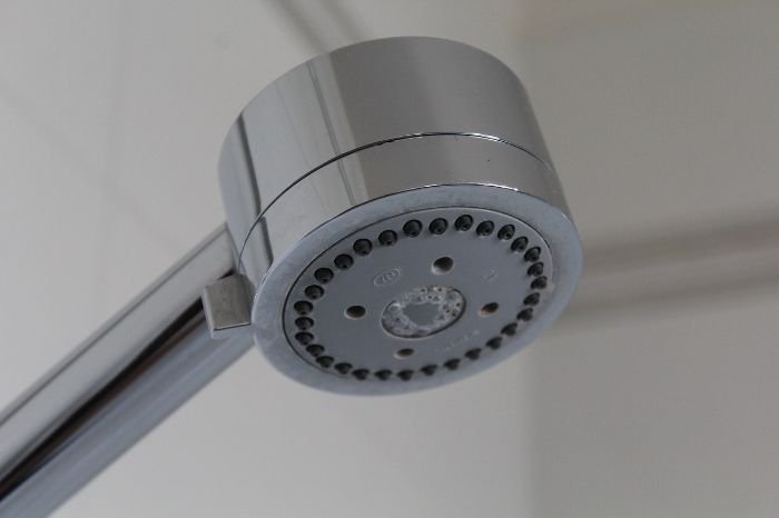 Close-up of a showerhead with limescale buildup, illustrating quick fixes for hard water stains using natural solutions