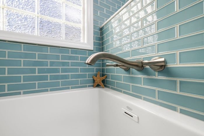 A clean bathroom with shiny blue tiles and grout, showcasing the importance of recognizing when cleaning is required to maintain hygiene and prevent buildup.