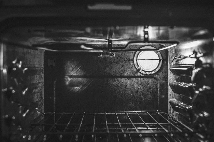 Interior of an oven with burnt food particles, illustrating how unclean ovens can produce smoke and harmful pollutants that affect air quality and lung health.