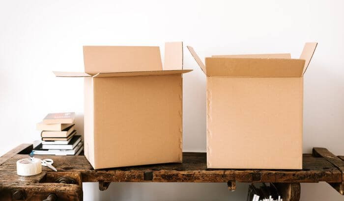 Two open cardboard boxes on a wooden table, symbolizing packing and move-out cleaning preparations
