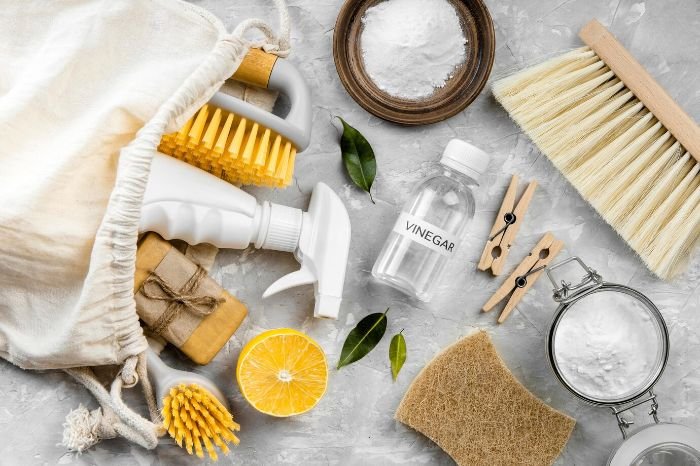 A collection of eco-friendly cleaning tools, including natural brushes, a spray bottle, baking soda, vinegar, and a lemon, illustrating tips for selecting truly eco-friendly cleaning products for a sustainable home.