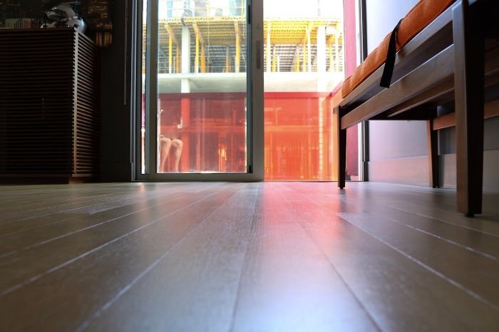 Close-up of clean hardwood floor by glass door, focusing on winter tenancy check-out cleaning to remove mud, salt, and slush