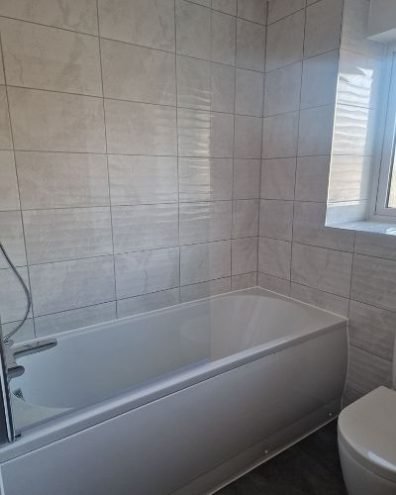 Clean and sparkling bathroom after end of tenancy cleaning in Buckhurst Hill, IG9, showcasing a spotless bathtub and tiled walls.