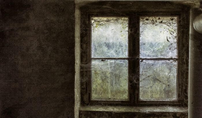 Dirty window with cobwebs and stains, illustrating the consequences of not cleaning walls and ceilings regularly.