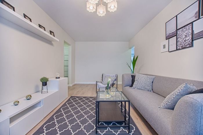 Modern living room with clean high-touch surfaces, including a glass coffee table, door handles, and a sleek, organized design.