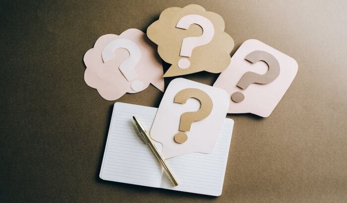 Notebook with a gold pen and paper cutouts of question marks, symbolizing a quiz about common cleaning mistakes.