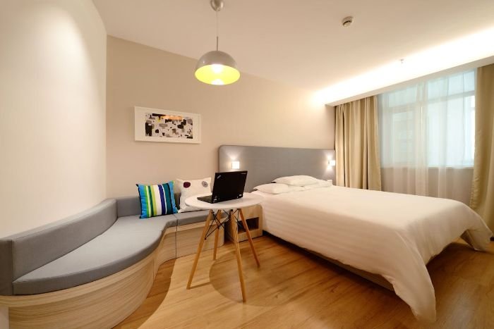 Cozy and relaxing bedroom ambiance with soft lighting, a comfortable bed, modern décor, and a laptop on a small table.