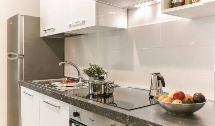 Modern and spotless kitchen showcasing hotel-level cleanliness with sleek countertops, organized appliances, and a fruit bowl for a fresh touch.